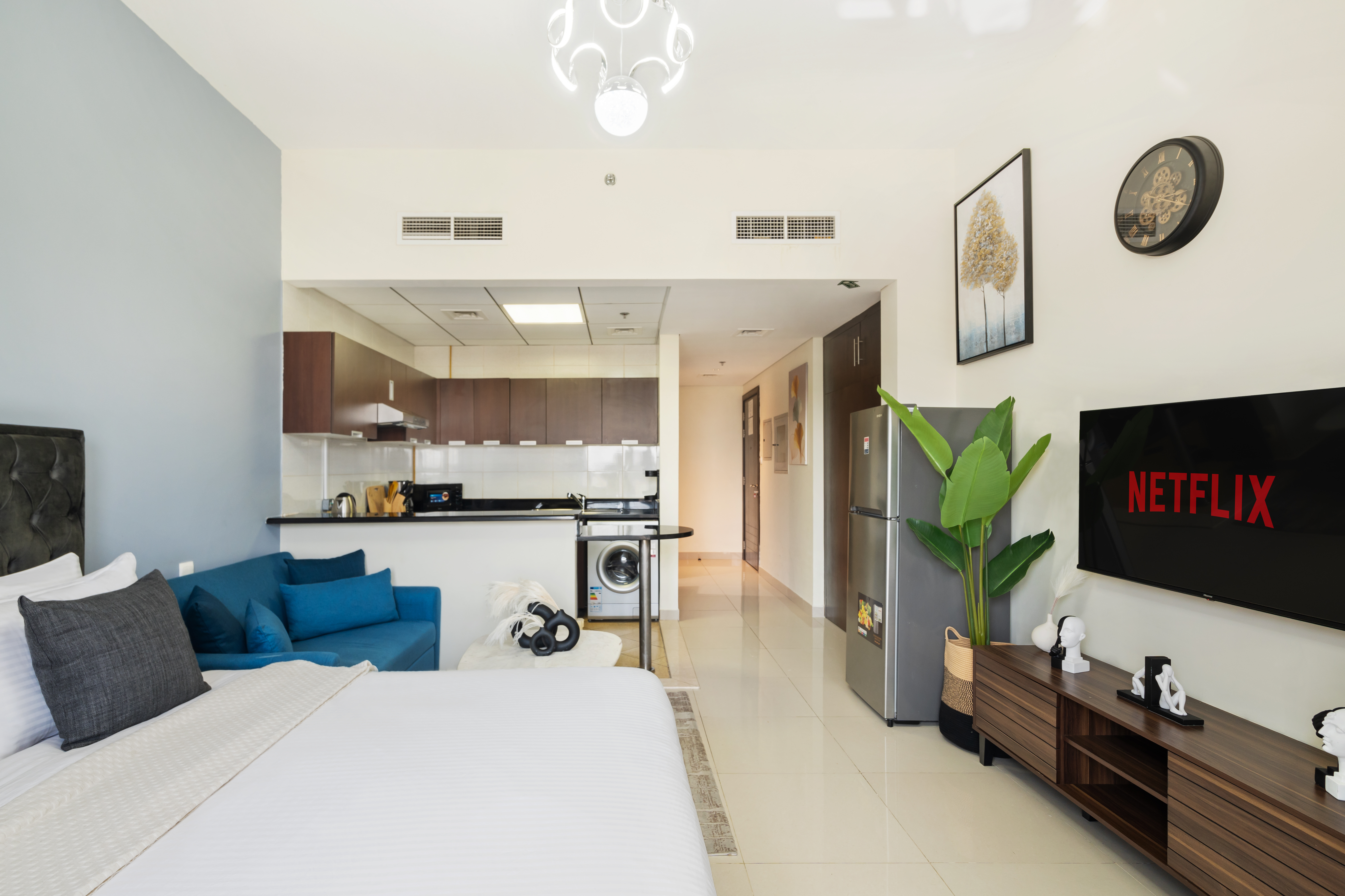 This open-concept living space radiates sophistication and style, seamlessly blending a plush seating area with a sleek kitchen and media center, creating a harmonious and inviting environment for relaxation, entertainment, and modern living.