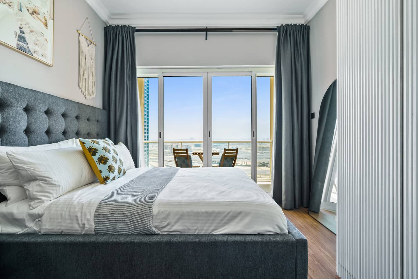 This luxurious apartment offers a serene and sophisticated retreat, with a neutral color palette, plush bedding, and a captivating panoramic view of the lake through the expansive windows, creating an exceptional guest