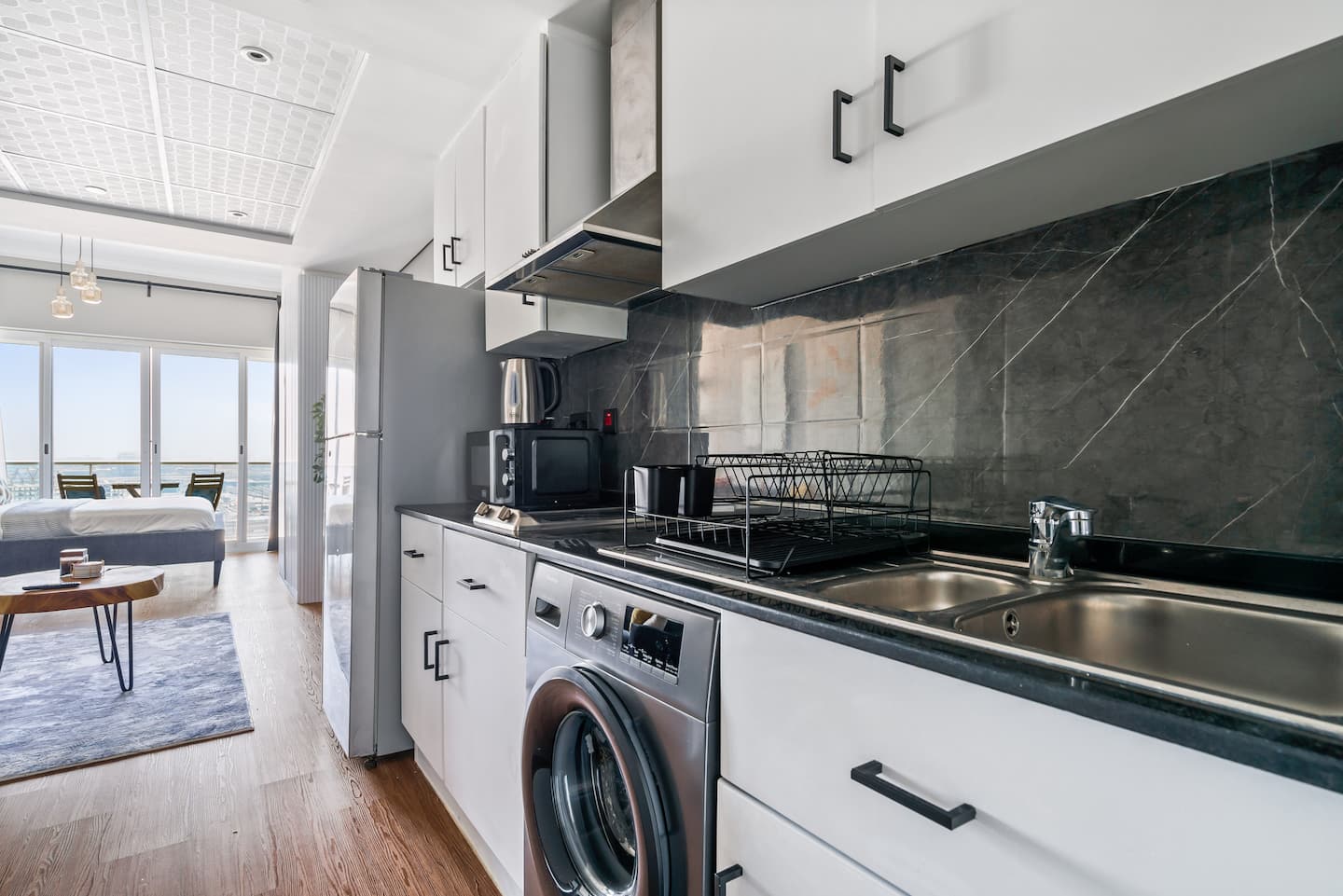 This modern kitchen boasts sleek wooden cabinetry, and a glossy black countertop, creating a clean and contemporary cooking space.