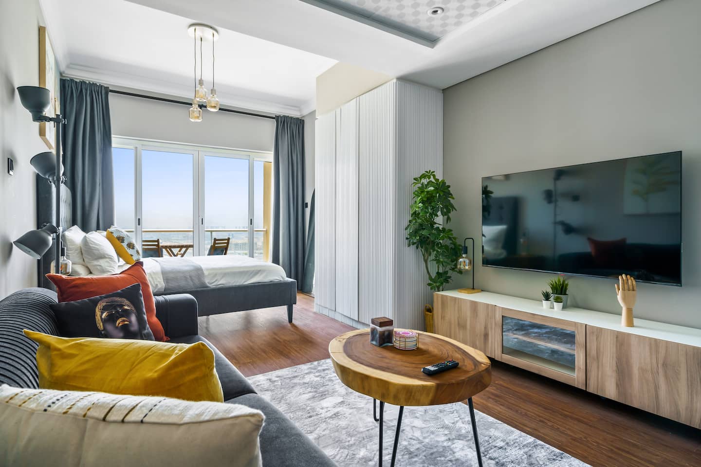 This open-concept living space radiates sophistication and style, seamlessly blending a plush seating area with a sleek kitchen and media center, creating a harmonious and inviting environment for relaxation, entertainment, and modern living.