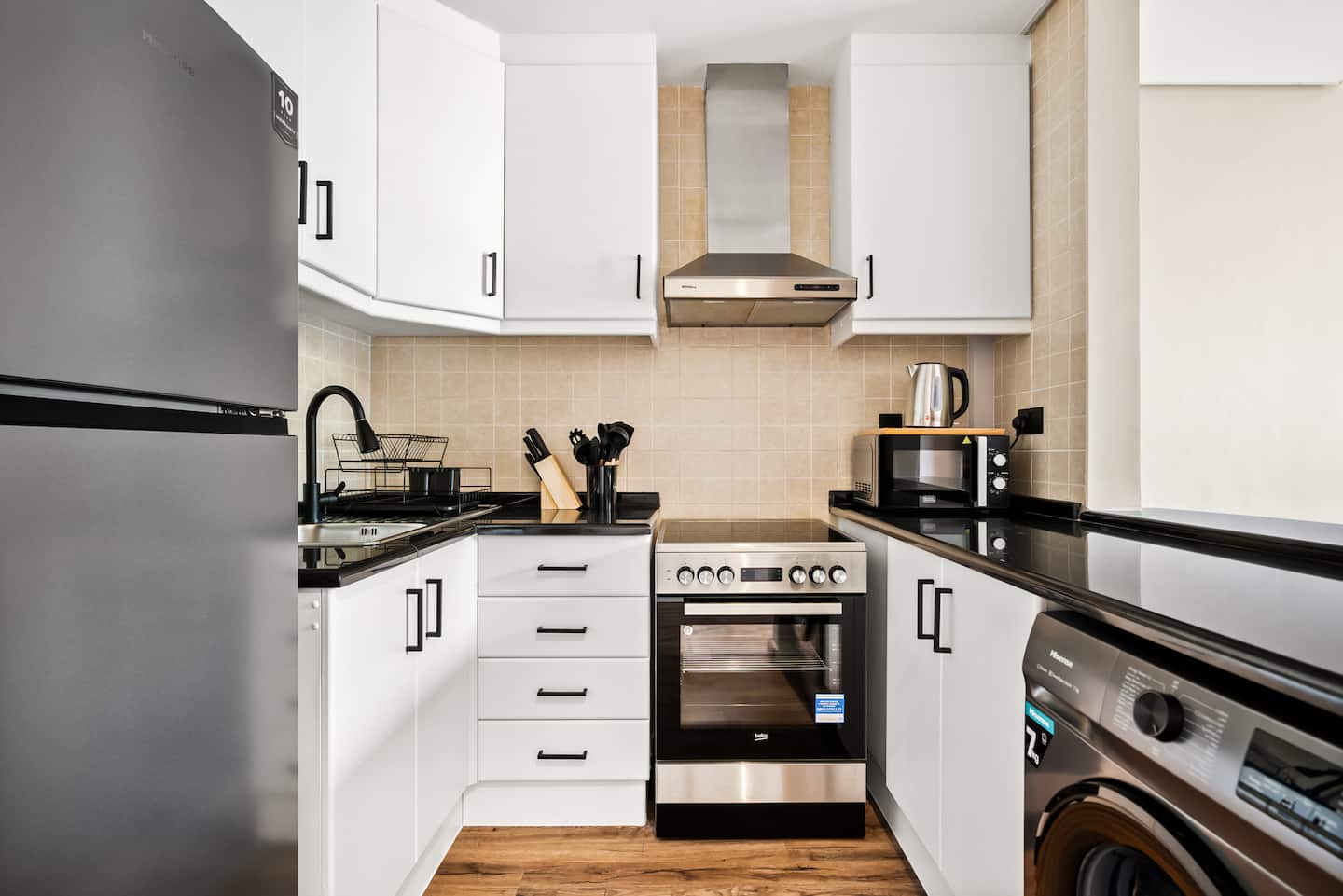 This modern kitchen boasts sleek white cabinetry, and a glossy black countertop, creating a clean and contemporary cooking space.